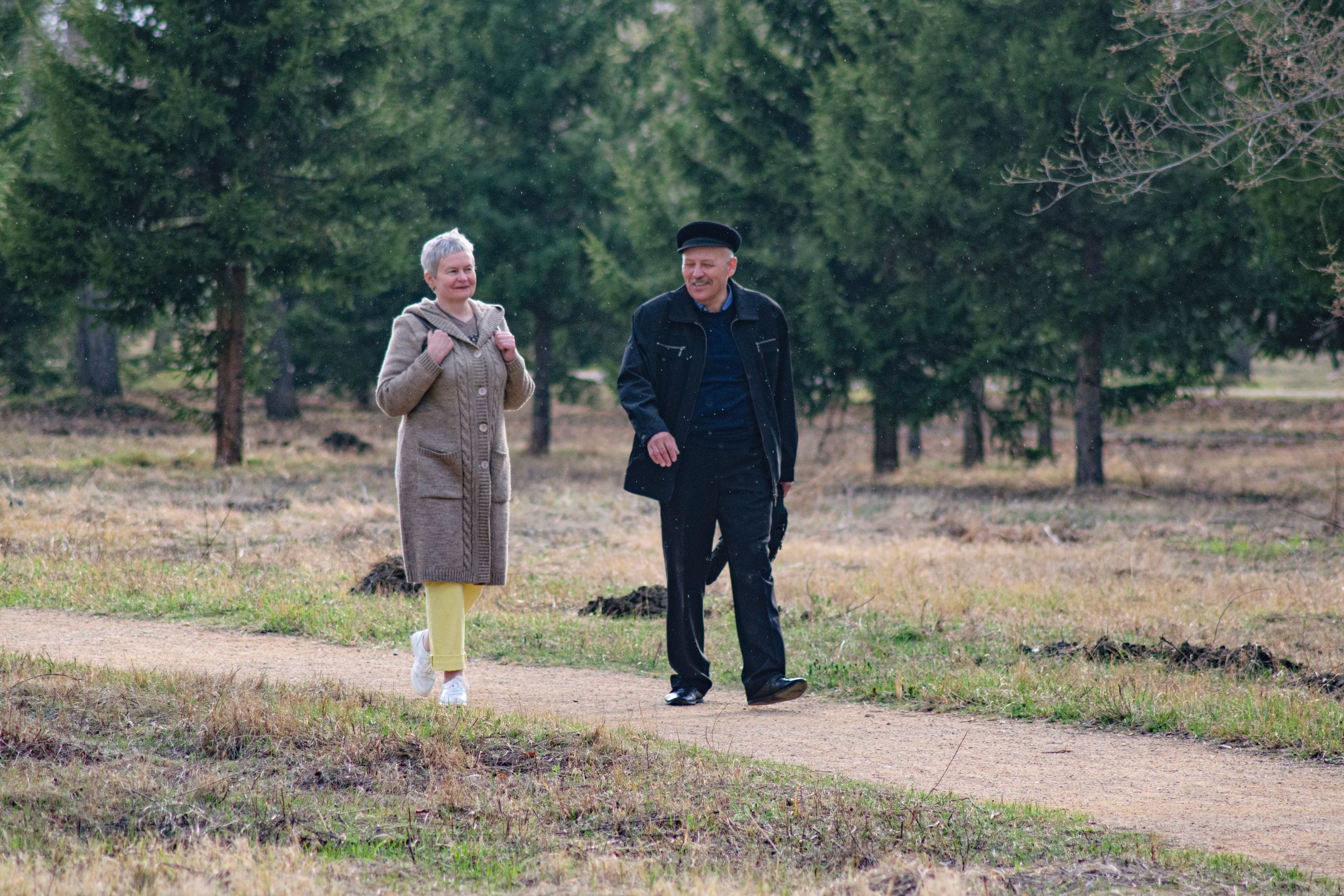 A couple walking together through a park in morning light